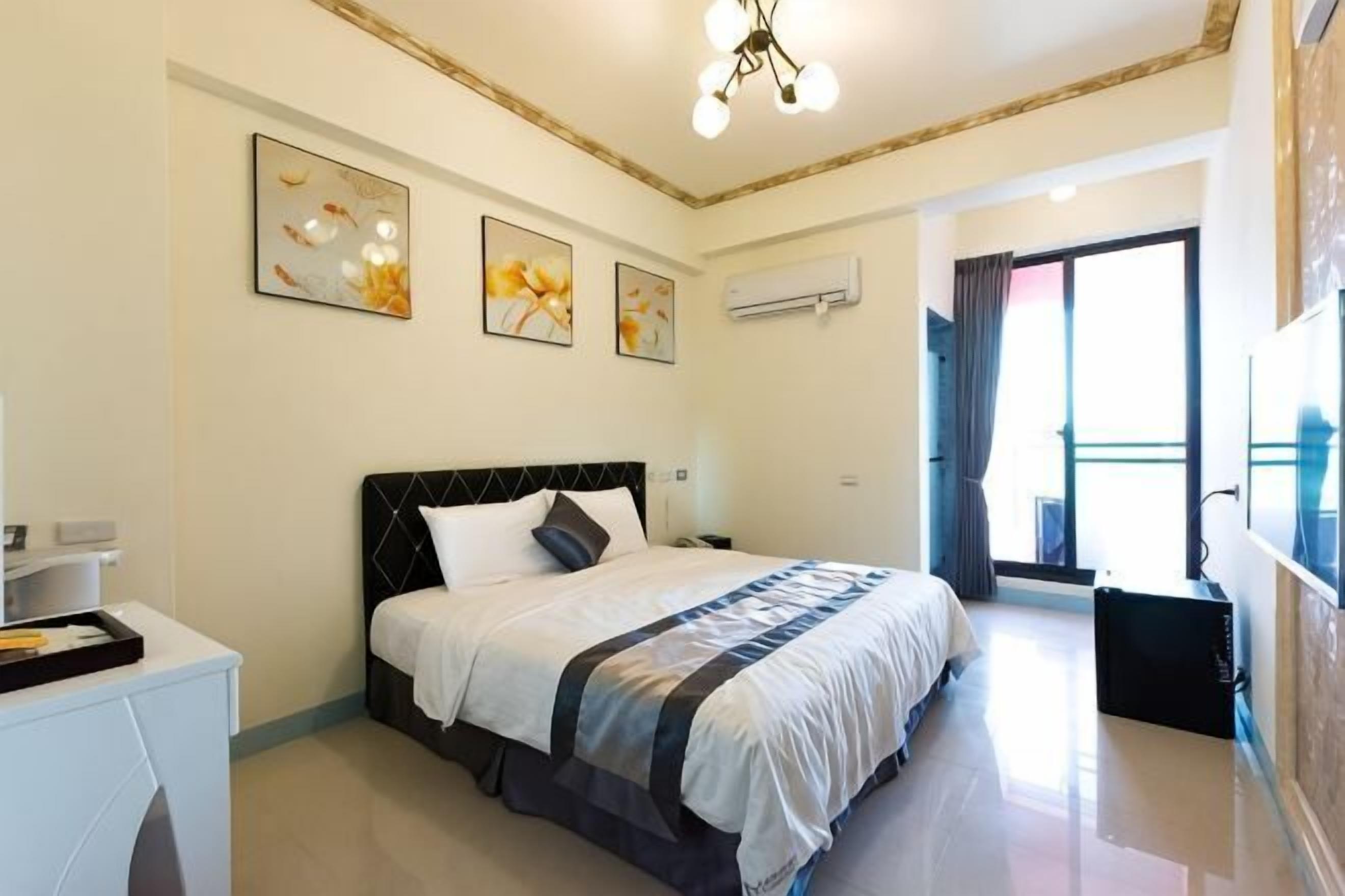 Een slaapkamer met een bed, nachtkastje en een kunstwerk aan de muur.