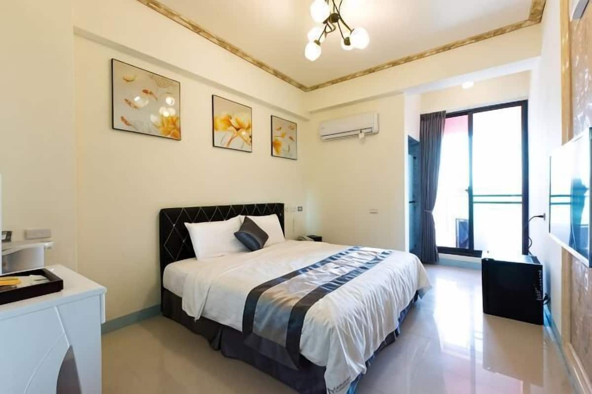 A bedroom with a bed, bedside table, and artwork on the wall.