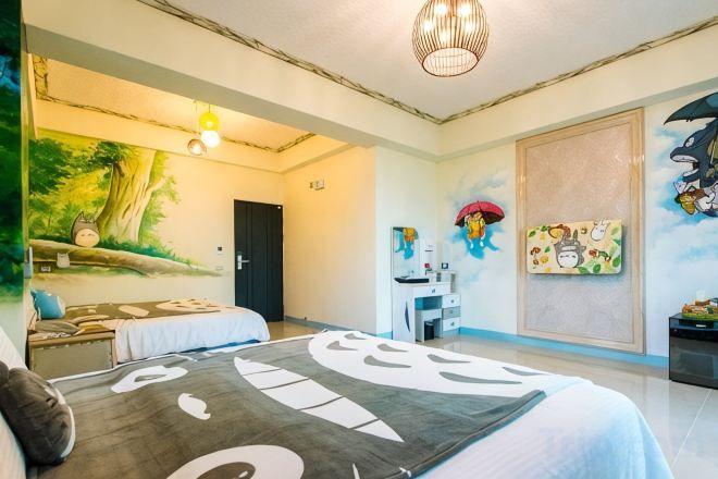 Una habitación de hotel con una cama, un escritorio, una silla y una pared con un mural.
