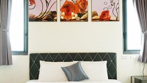 Una cama con cabecera, almohadas y un cuadro floral en la pared.