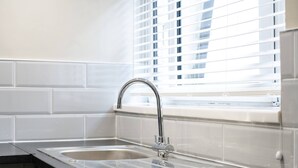 Una cocina moderna con un lavamanos de acero inoxidable y una ventana con persianas.