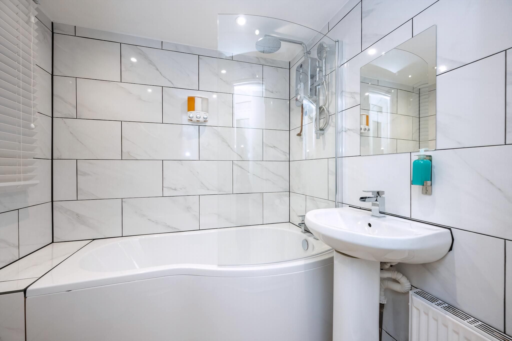 Un baño moderno con bañera, lavamanos, ducha y espejo.