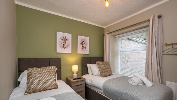 Una habitación de hotel con dos camas, una mesita de noche con lámpara y una obra de arte en la pared.