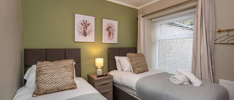 Une chambre d’hôtel avec deux lits, une table de chevet avec une lampe et des œuvres d’art accrochées au mur.