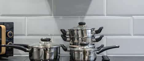 A kitchen with a black range hood, two pots on the stove, and a microwave below.