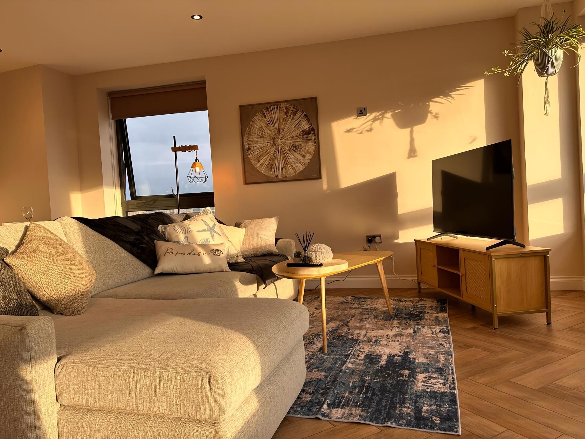 A living room with a sofa, coffee table, TV stand, and a large window.
