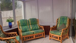 A sunroom with wicker furniture and a potted plant. - Swansea 3 Bedroom Home With Parking & Garden (Swansea)