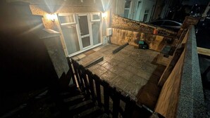 A rooftop patio with a wooden deck, a sliding glass door, and a small garden area. - City Escape 1 Bedroom Flat in Swansea Centre (Swansea)