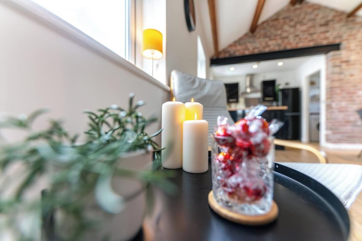 Gemütliche Innenraumgestaltung mit einem Tisch, der Kerzen und eine dekorative Glasvase beherbergt.