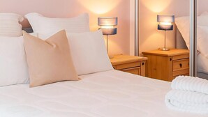 A neatly made bed with white linens, two bedside tables with lamps, and a wooden nightstand. - Reading Retreat 1 Bed With Private Parking (Reading)