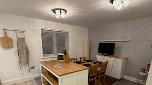 A compact kitchen with a dining area, wooden flooring, and a ceiling light fixture. - Reading Retreat 1 Bed With Private Parking (Reading)