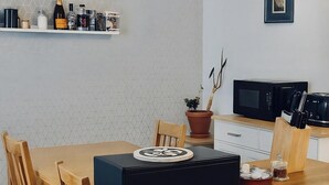 A modern kitchen with a wooden table, chairs, a microwave, and a potted plant. - Reading Retreat 1 Bed With Private Parking (Reading)