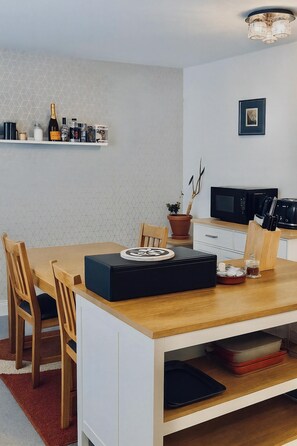 A modern kitchen with a wooden table, chairs, a microwave, and a potted plant. - Reading Retreat 1 Bed With Private Parking (Reading)