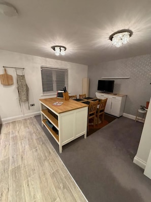 A compact kitchen with a dining area, wooden flooring, and a ceiling light fixture. - Reading Retreat 1 Bed With Private Parking (Reading)