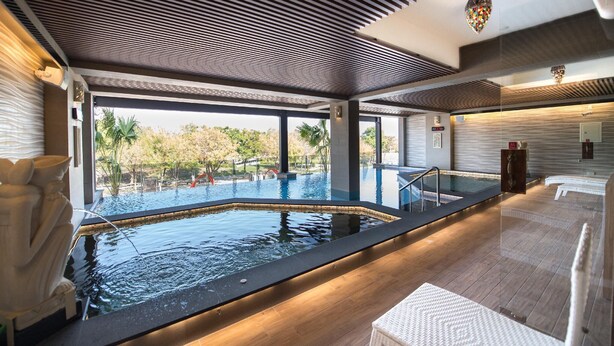Uma piscina coberta moderna com vista desimpedida para a paisagem circundante, um deck de madeira e uma parede de pedra.
