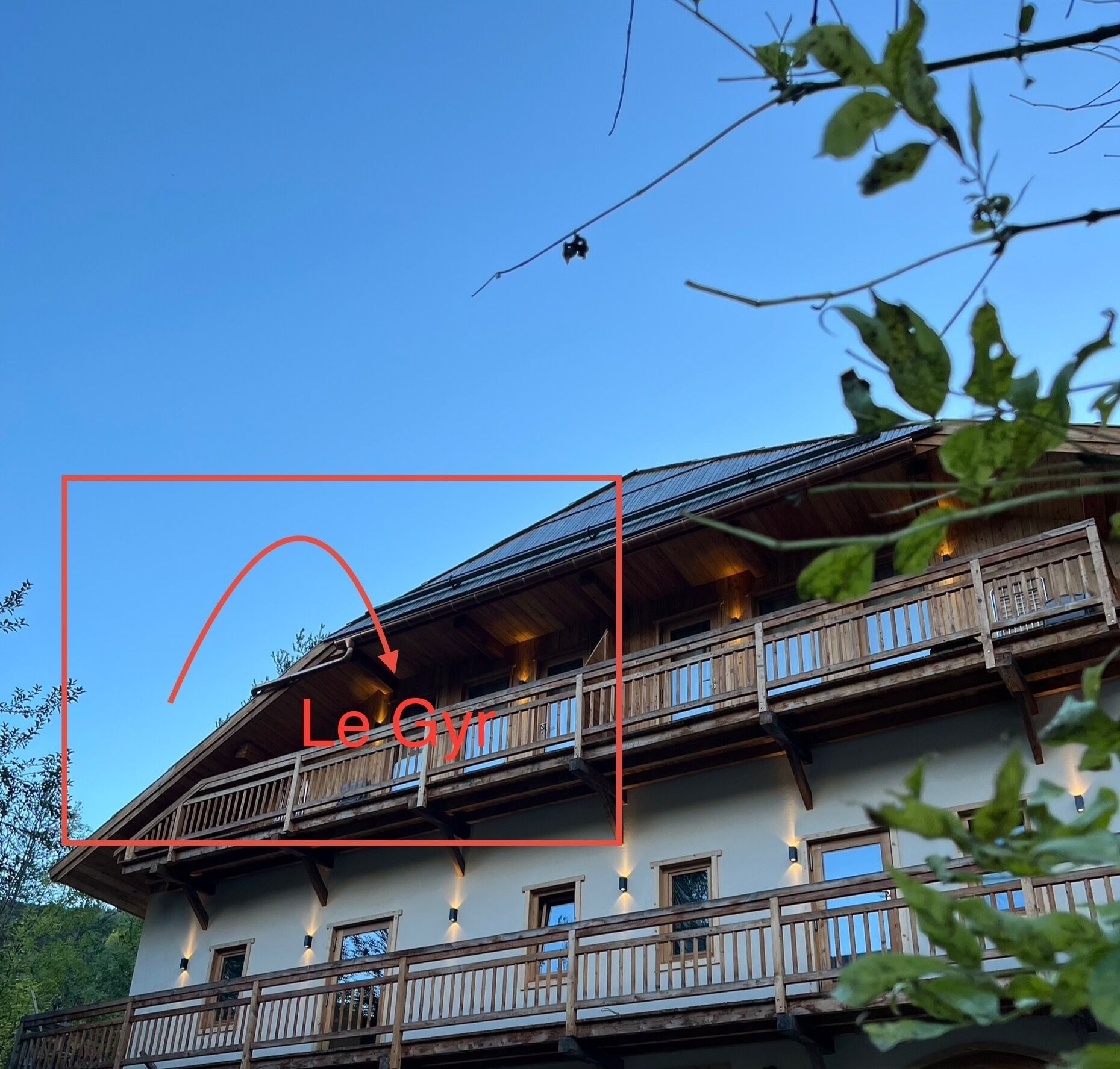 Un edificio de varios pisos con un balcón de madera y un techo a dos aguas.