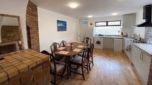 A compact kitchen with a dining area, a brick fireplace, and a window with a view.