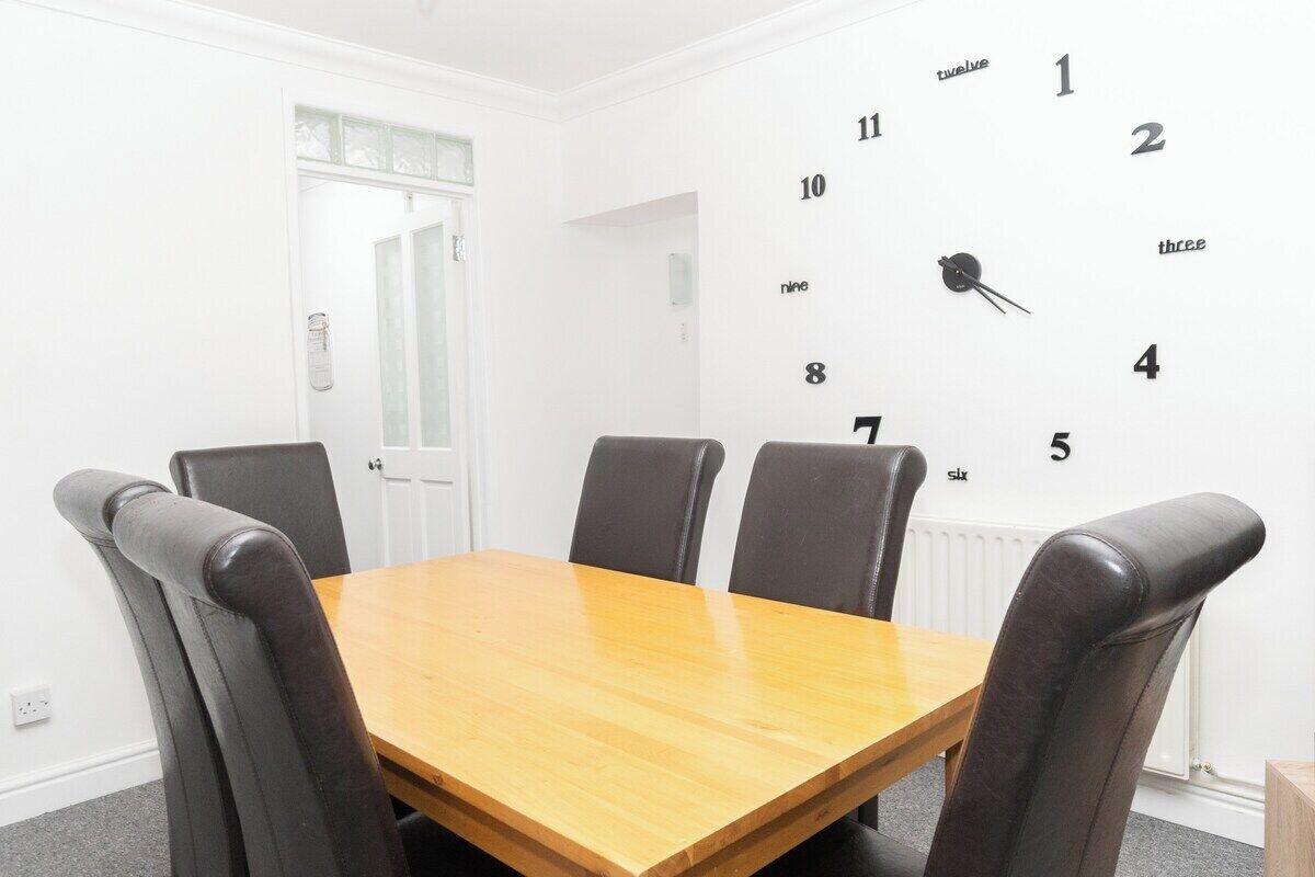 A conference room with a wooden table and four black leather chairs.