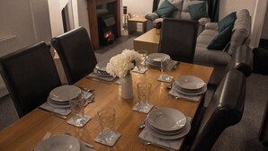 A dining area with a wooden table set for four, surrounded by chairs. - Family-friendly 3-bed House in Swansea (Swansea)