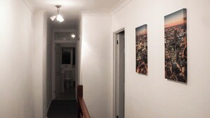 A hallway with a staircase leading to a door, two framed cityscape pictures on the wall, and a ceiling light fixture. - Family-friendly 3-bed House in Swansea (Swansea)