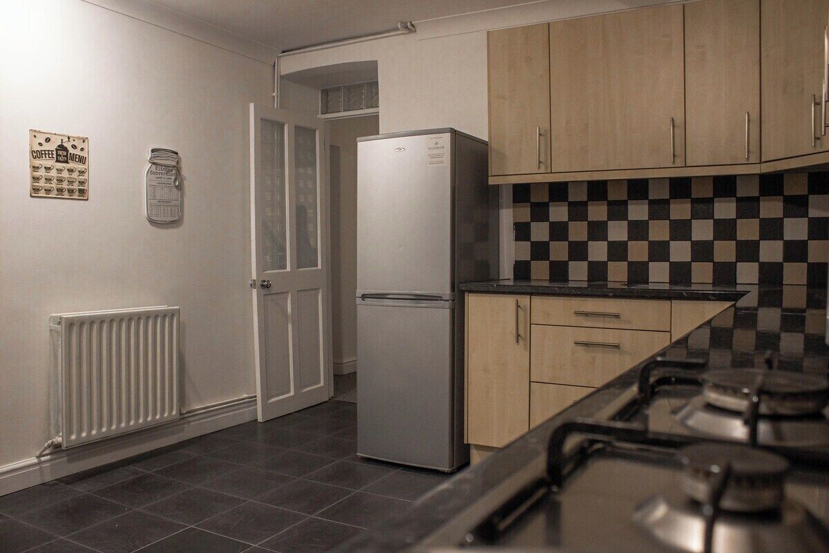 A kitchen with a refrigerator, a stove, and a tiled backsplash.
