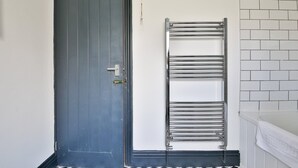 Un baño con puerta cerrada, un perchero para toallas y una pared con azulejos.