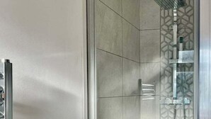 Une cabine de douche moderne avec un motif géométrique en carreaux et un pommeau de douche à main.
