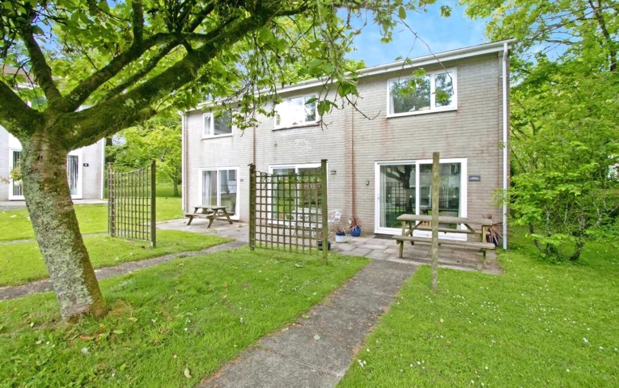 A two-story building with a brick facade, a gated entrance, and a paved patio area with picnic tables.