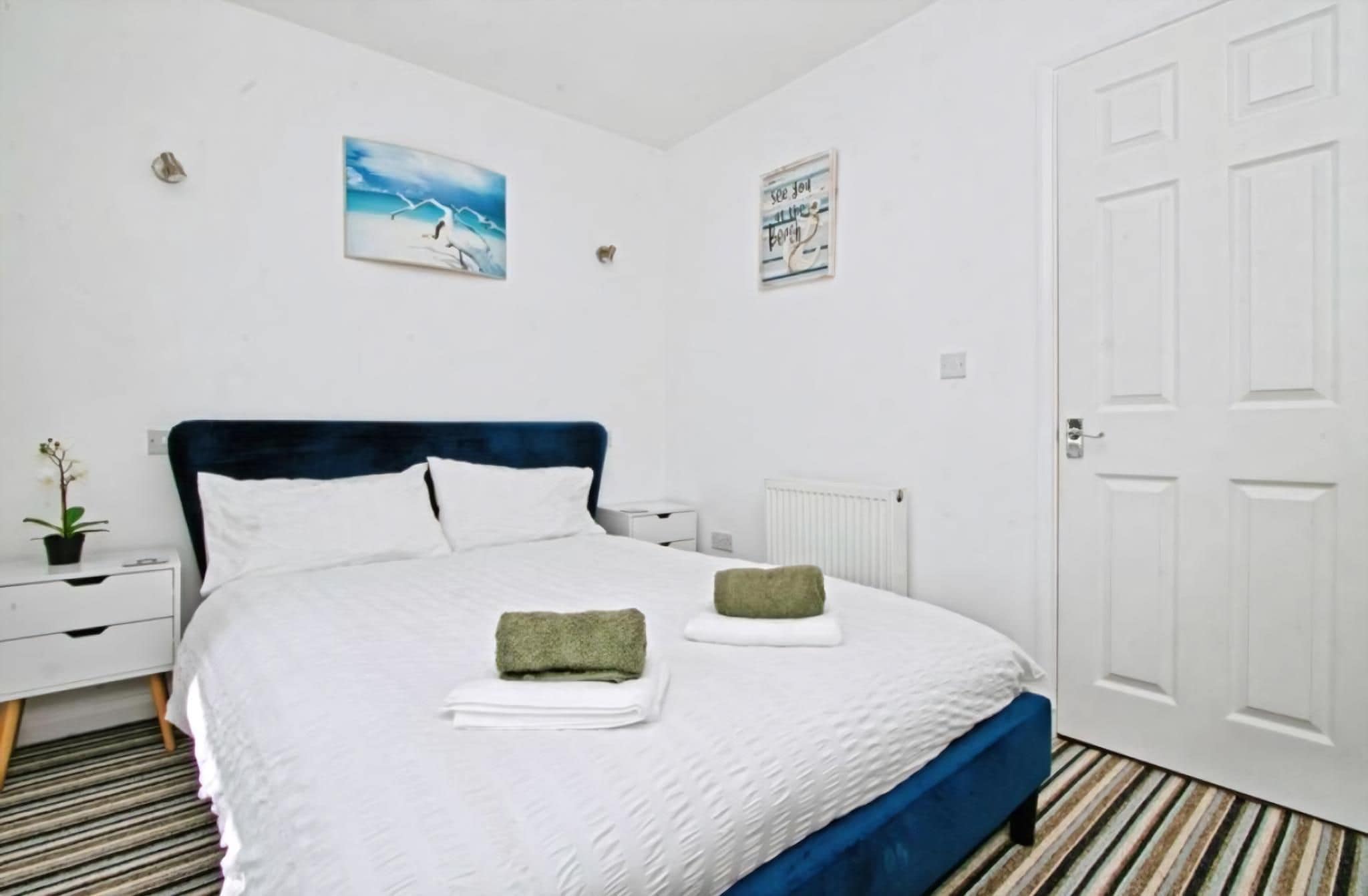 Een slaapkamer met een bed, witte muren, een deur en een radiator.
