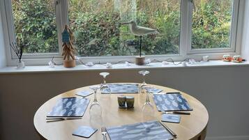 A round dining table with placemats, cutlery, and wine glasses set for four.