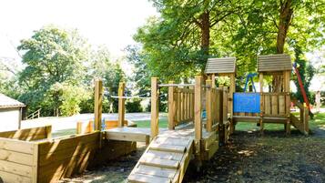 A wooden playground with a slide and climbing structures.