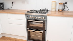 A kitchen with a stainless steel gas stove, a double oven, and a coffee maker on the countertop.