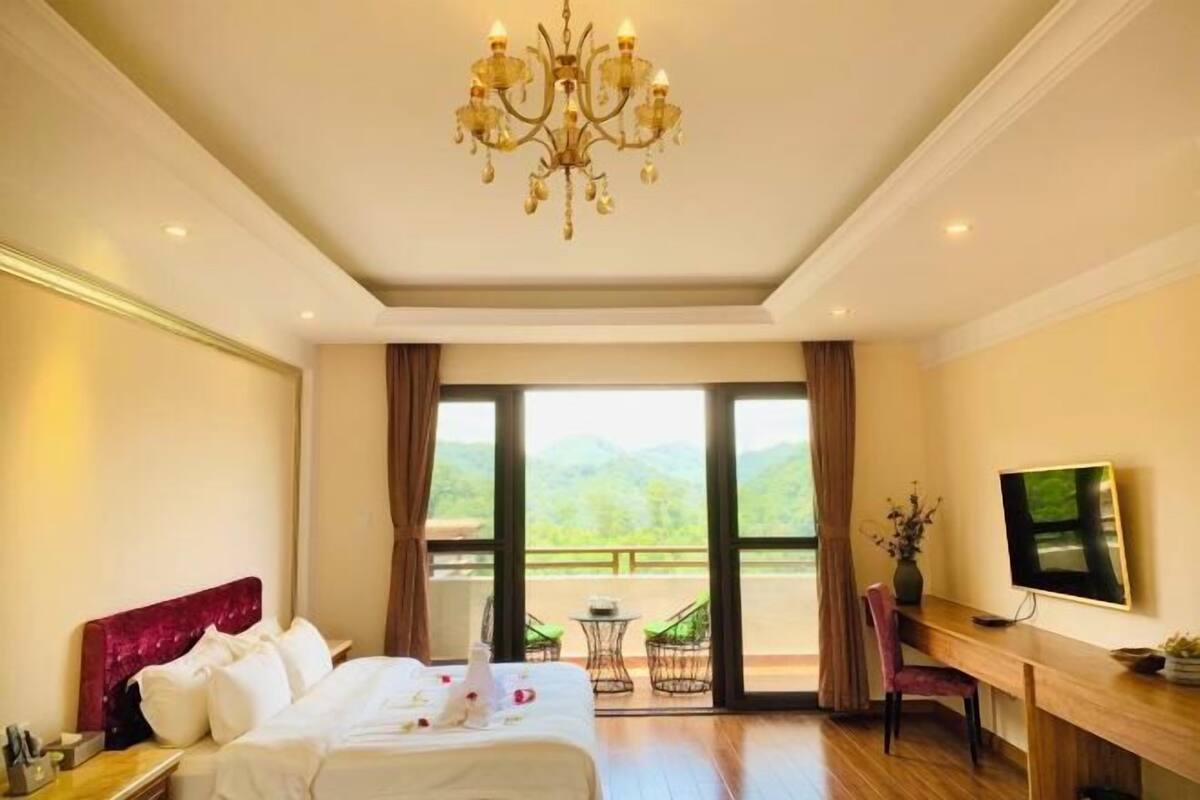 A hotel room with a bed, a desk, a television, and a view of the outdoors.
