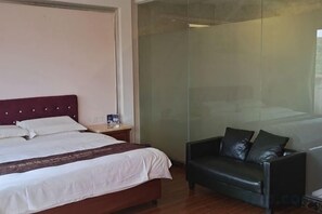 Une chambre d’hôtel avec un lit, une table de chevet, un canapé en cuir et une cloison en verre.