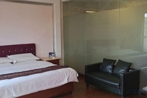 Una habitación de hotel con cama, mesita de noche, sofá de cuero y separador de vidrio.