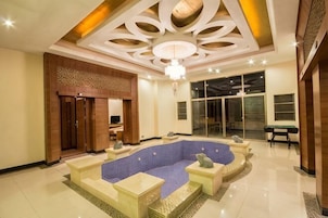 Um hall amplo com área de estar central, um candelabro e uma grande janela.