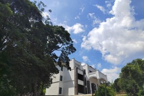 A modern building with a white facade and multiple windows, surrounded by lush greenery. - Nankunshan Shihe Wonder Resort Villa (Longmen)