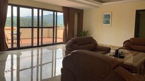 A spacious living room with a large sliding glass door leading to a balcony, a comfortable sofa set, and a small table with a coffee maker. - Nankunshan Shihe Wonder Resort Villa (Longmen)