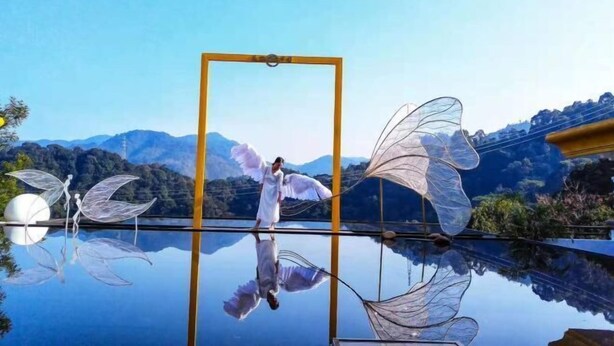 A serene outdoor scene with a reflective pool, a person in white, and decorative wings. - Nankunshan Shihe Wonder Resort Villa (Longmen)