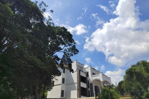 Um edifício com fachada branca, várias janelas e céu claro com nuvens.