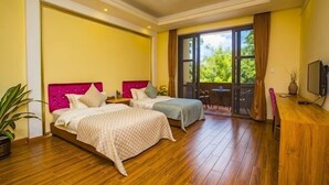 A hotel room with two beds, a wooden floor, a balcony with a table and chairs, and a TV on a wooden cabinet. - Nankunshan Shihe Wonder Resort Villa (Longmen)