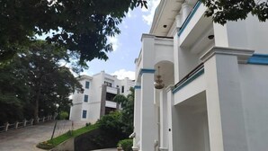 A white building with a staircase leading up to a balcony, surrounded by greenery and a paved area. - Nankunshan Shihe Wonder Resort Villa (Longmen)