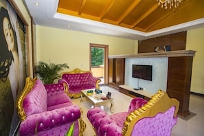 Una habitación con chimenea, televisión y mobiliario tapizado color púrpura.