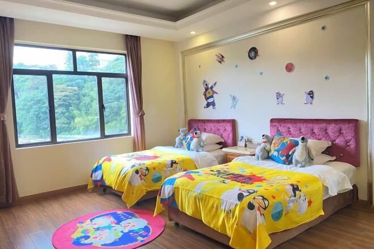 A bedroom with two beds, a window, and a wall decorated with cartoon characters.