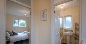A bedroom with a bed, a window, a bedside lamp, and a framed picture on the wall. - Comfortable 4-bed Home With Free Parking (Swansea)