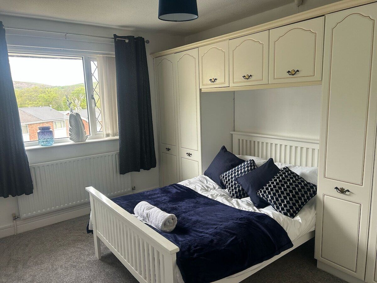 A bedroom with a bed, white wardrobe, and a window with curtains.