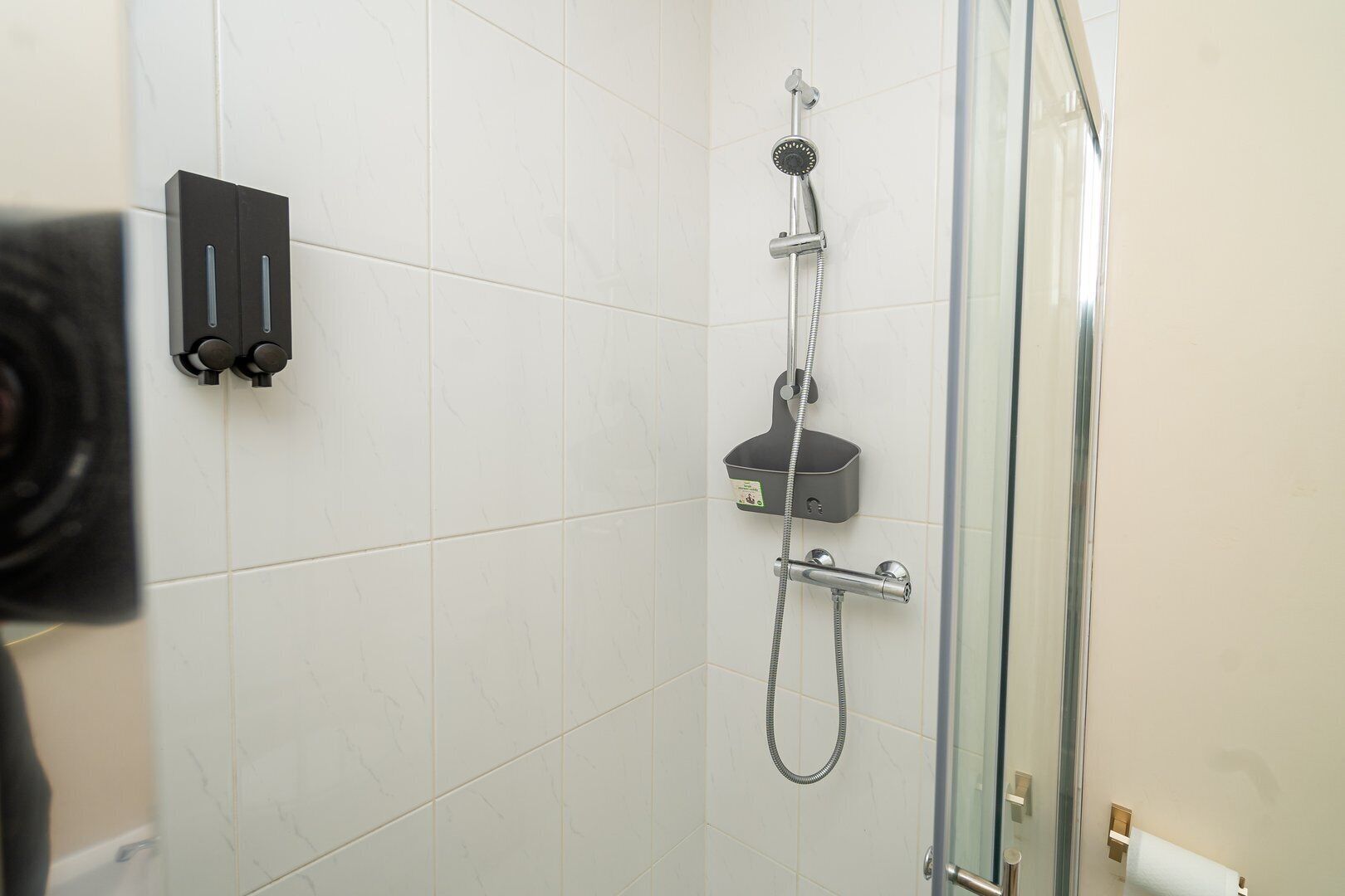 Une douche équipée d’un pommeau de douche à main et d’un robinet à main.