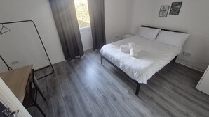 Una camera da letto con un letto, una scrivania e una finestra con tende.