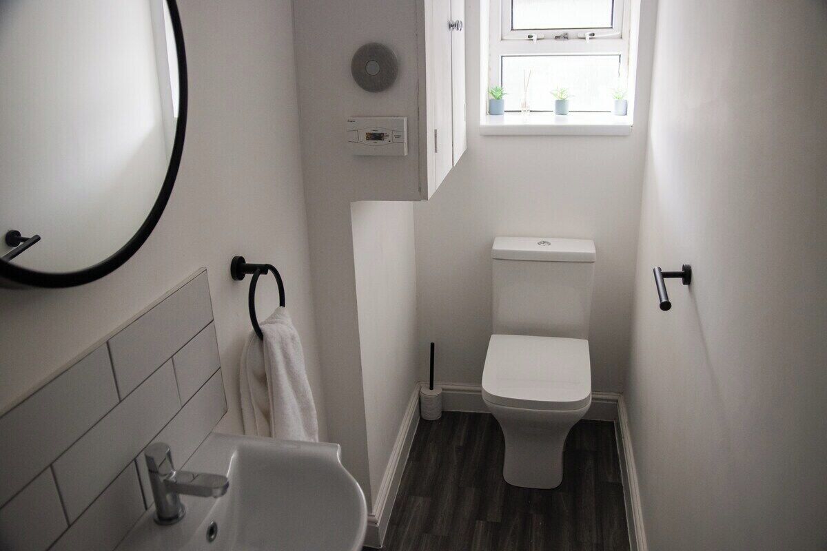 A small, modern bathroom with a toilet, sink, and a window above the toilet.
