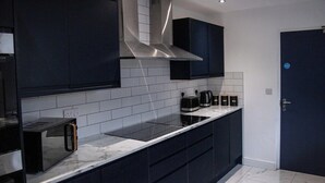 Una cucina moderna con mobili scuri, una cappa aspirante in acciaio inossidabile, un piano cottura a induzione nero e un forno integrato.